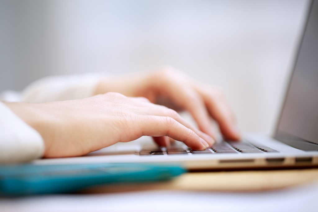 Image of hands on a keyboard close up - side view.