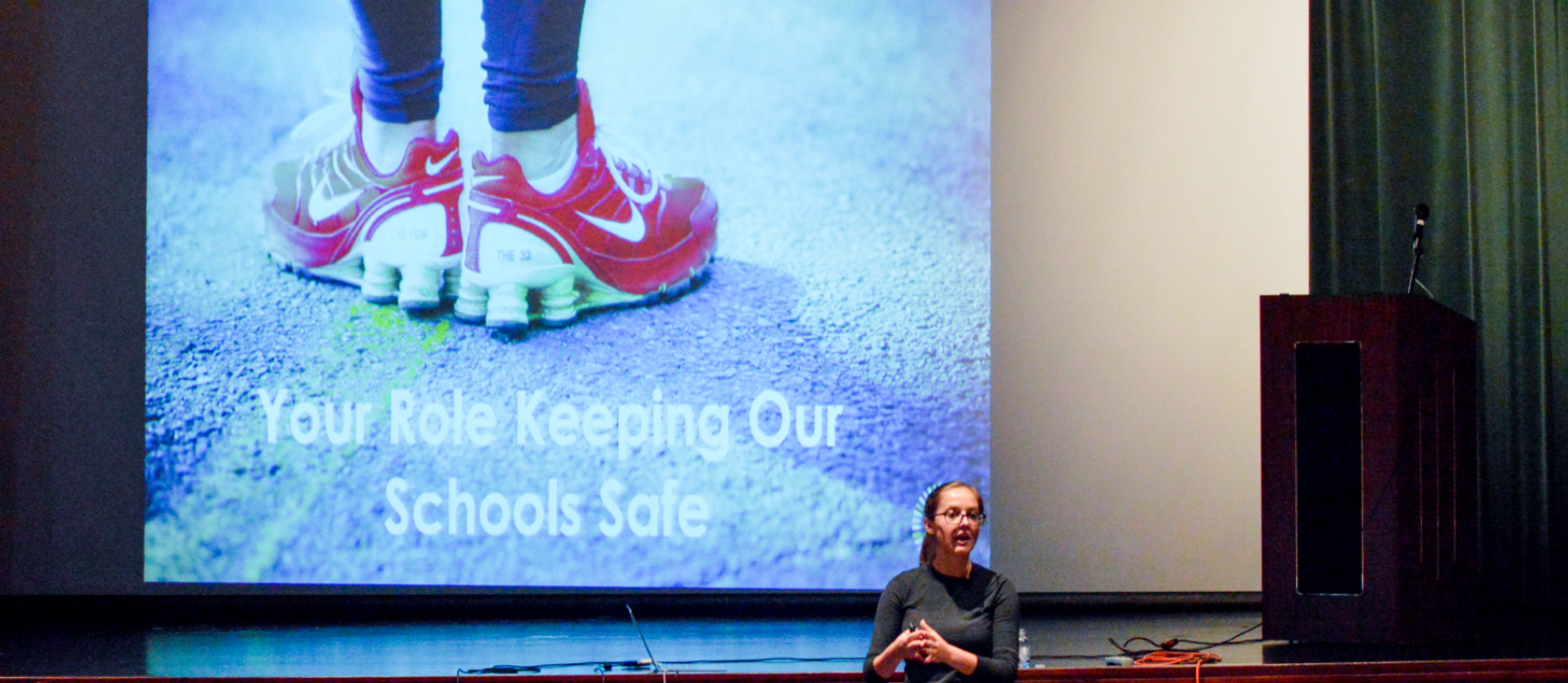 A presentation screen showing an image of shoes and the quote "Your role in keeping our schools safe"